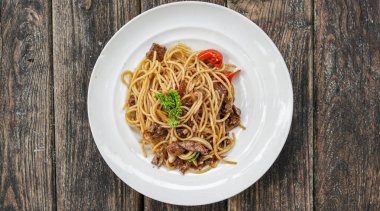 Masanın üstünde beyaz tabaklı spagetti.