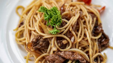 Masanın üstünde beyaz tabaklı spagetti.