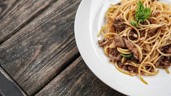 Masanın üstünde beyaz tabaklı spagetti.