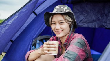 Genç Asyalı kadın çadırda kahve içiyor.