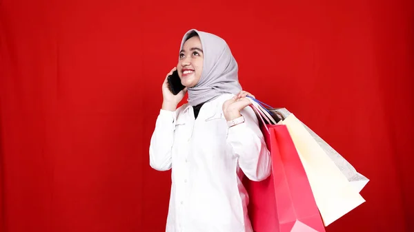 Asian hijab woman calling with hold  shopping bag