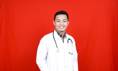 Boynunda steteskopla gülümseyen genç bir erkek doktor.