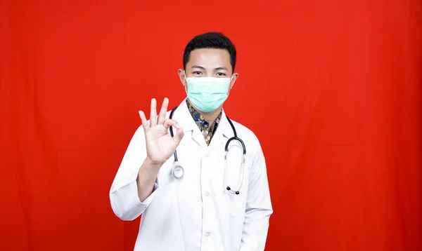 Azji Mężczyzna Lekarz Nosić Maskę Gest Izolowane Czerwone Tło — Zdjęcie stockowe