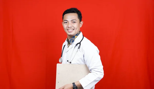 Ásia Masculino Médico Segurando Prancheta Isolado Vermelho Fundo — Fotografia de Stock