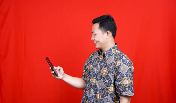 Asyalı Adam Heyecanlıydı Cep Telefonunu Batik Giyim Izliyordu — Stok fotoğraf