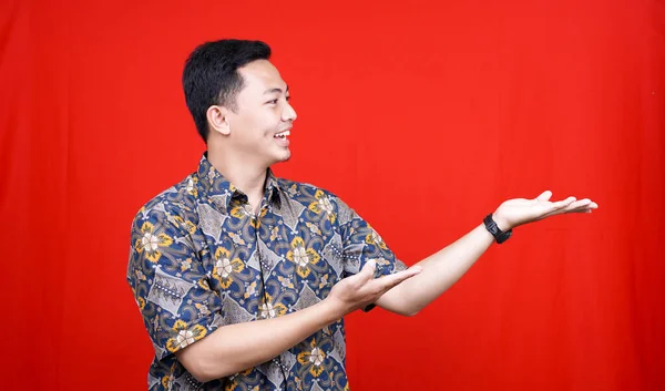 Ásia Homem Vestindo Batik Apontando Espaço Branco Isolado Vermelho Fundo — Fotografia de Stock