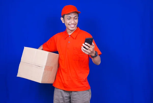 Delivery Man Boldog Keres Telefon Elszigetelt Kék Háttér — Stock Fotó