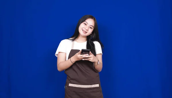 Asiático Mujer Tendero Feliz Mirada Teléfono Aislado Azul Fondo —  Fotos de Stock