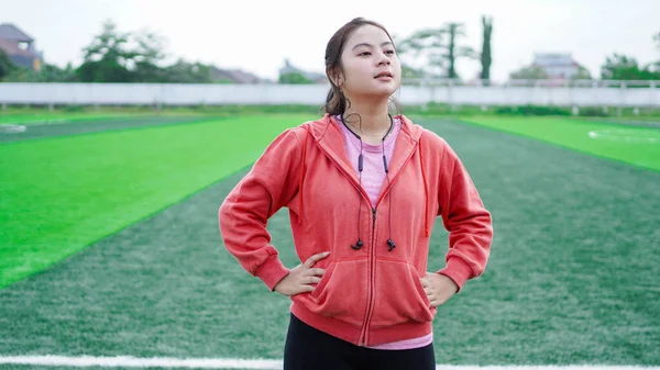 亚洲女人跑步后休息 穿着夹克和耳机 — 图库照片