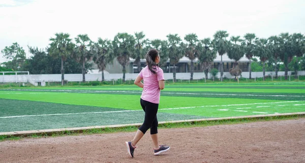 asian woman athlete running on track. back view