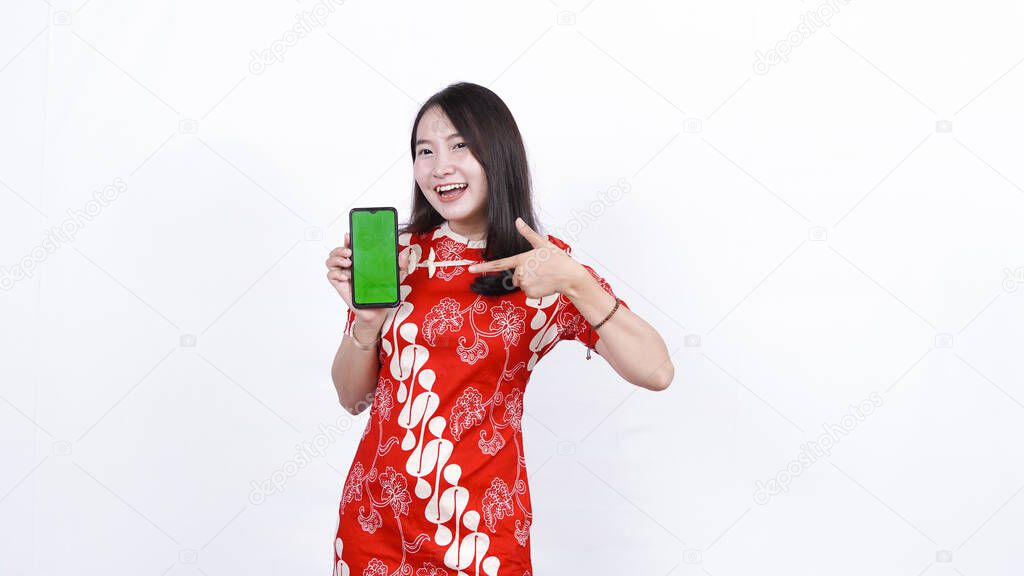 asian woman wear traditional chinese dress pointing green screen phone isolated with background
