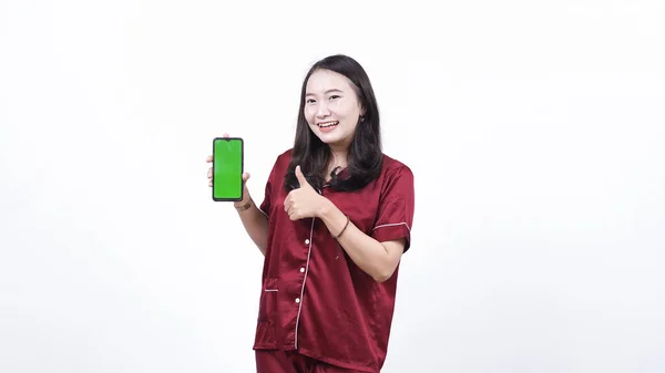 パジャマ姿の女性は緑の画面の電話機を持ってる — ストック写真