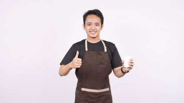 Önlük giyen adam beyaz bir arka planda duruyor. Elinde bir bardak tutuyor.