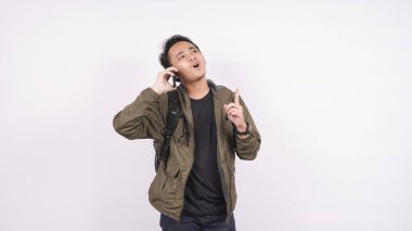 Asyalı adam arıyor ve beyaz arka planda bir şeyler düşünüyor.