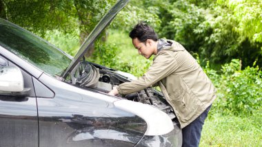 Asyalı adam kaputu açtı ve arabayı kontrol etti.