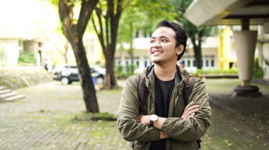 Sırt çantalı gülümseyen ve kameraya bakan Asyalı adamın portresi.