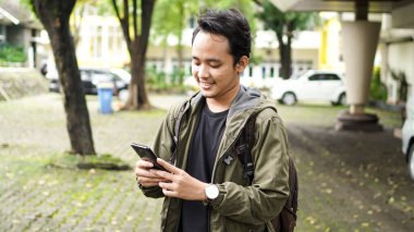 Asyalılar cep telefonu tutarken sırt çantası takarlar.