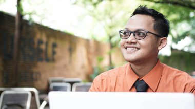 Genç Asyalı girişimciler dizüstü bilgisayara bakıyor