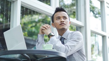 Genç girişimciler dizüstü bilgisayarla otururken düşünür.