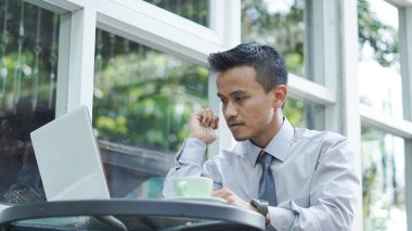 Genç girişimciler dizüstü bilgisayarla otururken düşünür.