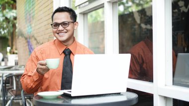 Girişimciler bilgisayarda çalışıyor, kahve içiyor ve gülümsüyor.