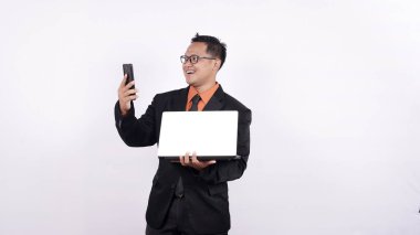 İş adamı dizüstü bilgisayar tutuyor ve izole edilmiş bir cep telefonuna bakıyor.