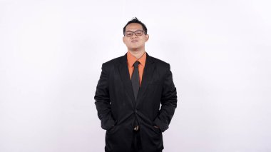 Genç işadamı beyaz bir arka planda kendine güvenen bir gülümsemeyle kameraya bakıyor.