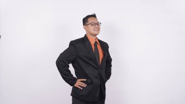 Genç işadamı beyaz bir arka planda kendine güvenen bir gülümsemeyle kameraya bakıyor.