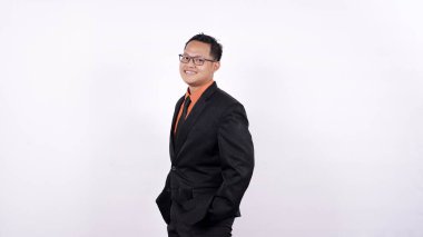 Genç işadamı beyaz bir arka planda kendine güvenen bir gülümsemeyle kameraya bakıyor.