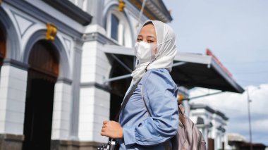 İstasyonun önünde trenle seyahat eden Asyalı kadınlar jilbab ve analog kamera takıyor.