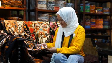 Asyalı kadınlar Batik 'i jilbab ve analog kamera giyerken görmek için seyahat ederler.