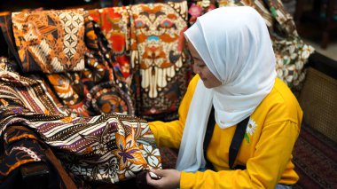 Asyalı kadınlar Batik 'i jilbab ve analog kamera giyerken görmek için seyahat ederler.