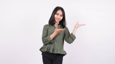 Mutlu genç kadın beyaz bir arka planda tek başına dikilirken işaret ediyor.