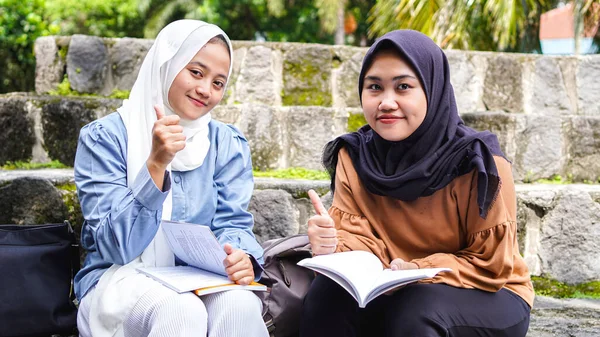 two Asian woman student friends discussing with ok gesture