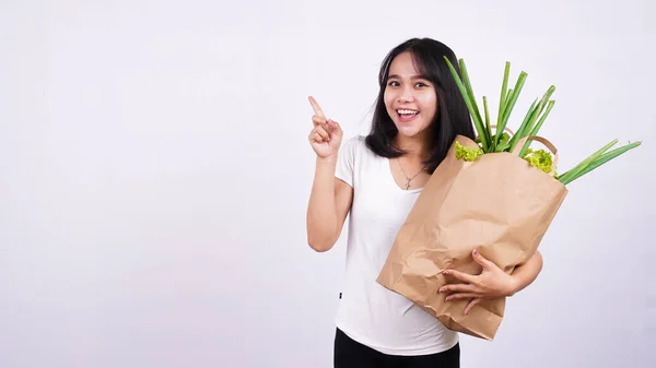 美丽的亚洲女人手里拿着一袋一袋袋袋的新鲜蔬菜 非常开心 手指手画脚地在孤立的白色背景上 — 图库照片#