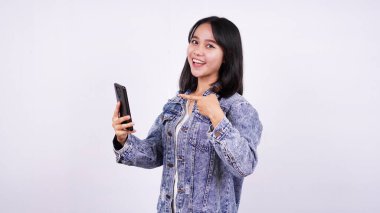 Kot ceket giyip gülümseyen Asyalı kadınlar telefonu izole edilmiş beyaz arka planda tutuyorlardı.