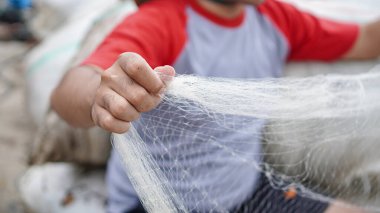 Genç bir balıkçının portresi sahilde bir balık ağı hazırlıyor.