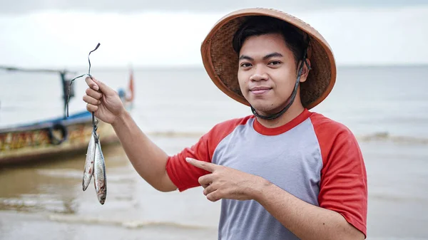 Šťastný Mladý Rybář Pláži Drží Své Úlovek Ryby Ukazuje Před — Stock fotografie