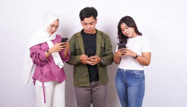 İki kadın ve erkek, beyaz arka planda telefon oyunu oynuyorlar.