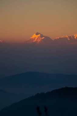 Güneşin son ışıkları altın tepelere vururken, trishul zirvesinin güzel manzarasının tadını çıkarıyorlar.