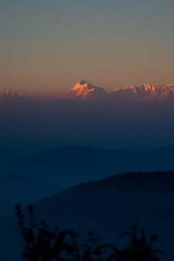 Güneşin son ışıkları altın tepelere vururken, trishul zirvesinin güzel manzarasının tadını çıkarıyorlar.