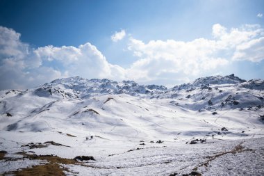 Açık dağ tarlaları, parlak bir gün ışığında kalın ve taze bir kar tabakasıyla kaplıdır.