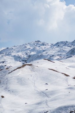 Açık dağ tarlaları, parlak bir gün ışığında kalın ve taze bir kar tabakasıyla kaplıdır.