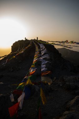 Gün batımında uttarakhand 'da kayalarda asılı Tibet bayraklarıyla dağ zirvesi