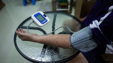 Yaşlı adam kolunu sardı ve tansiyonunu ölçmek için sphygmomanometre kullandı..