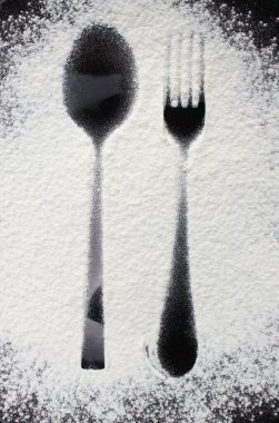 yiyecek konsepti - Un ve pudra şekerine çatal ve kaşık izli siyah tabağın üst görünümü.