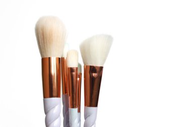 Beyaz arka planda 6 adet makyaj fırçası seti. 5 'i bir arada ve tablonun sol tarafında daha büyük bir toz fırçası ile dengelenmiş..