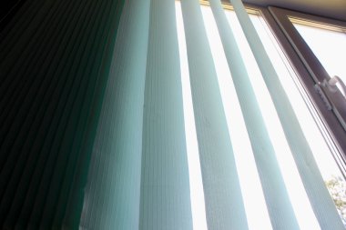 Pencerenin arka planına karşı kapalı dikey panjurlar.