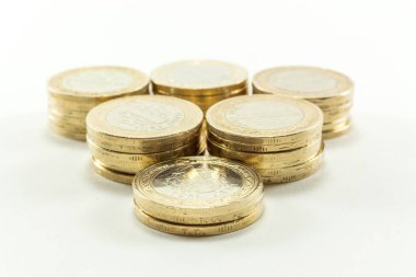 Tasarruf ve mali büyümeyi sembolize eden, temiz beyaz bir arkaplan üzerine yerleştirilmiş çok sayıda Türk Lirası bimetalik sikkesi yığını.