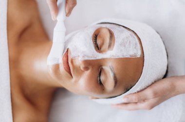 Güzellik salonunda yüz maskesi yapıyorum. Kozmetik uzmanına gidiyorum. Yüzünde maske olan beyaz kadın yüzü yukarıdan yakından çekilmiş..